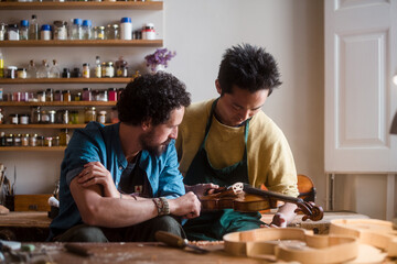 Two violin luthiers discussing about it's restoration process