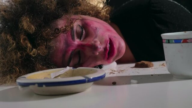 young woman brutalized by drugs with her head resting on the table