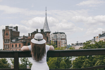 A young girl in a hat stands in front of a castle. Woman in a white hat