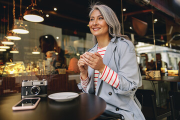 Charming mature female sitting at urban cafe