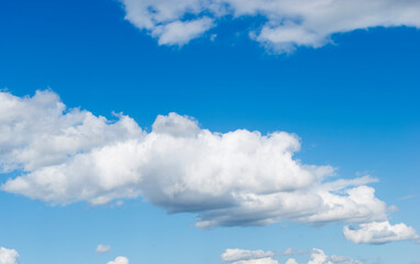 Sunny fluffy cumulus clouds at summer sky.