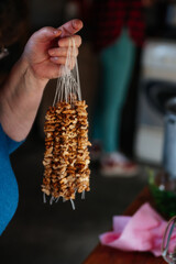 Close-up: hand holding walnut in a row on a string, preparing the base for churchkhela.