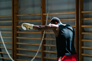 Black boxer practicing jabs in gym