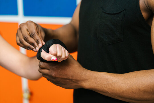 Crop coach helping boxer to bandage hand