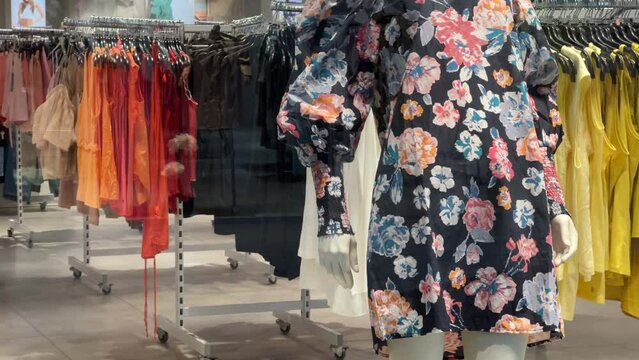 Women's clothing store with a summer collection. Multicolored dresses hang on hangers