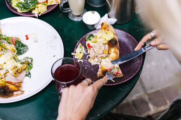 Faceless visitor eating pizza over wine for lunch 