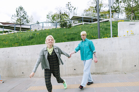 Couple keeping hand in hand and running together through crosswalk