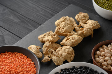 Soy meat and legumes, overhead flat lay shot on a dark rustic wooden background