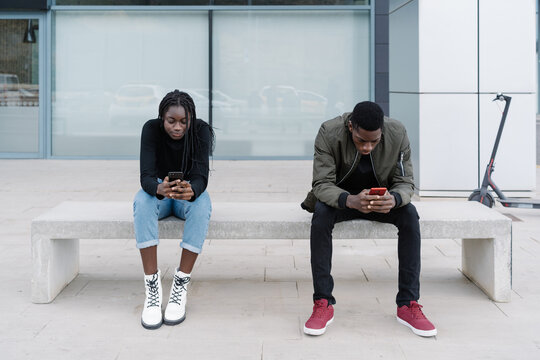 Black man and woman using smartphones on street