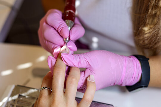 A manicurist treats a woman's nails and cuticles in a beauty salon