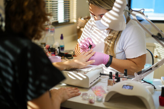 A manicurist treats a woman's nails and cuticles in a beauty salon