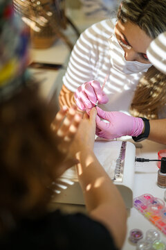A manicurist treats a woman's nails and cuticles in a beauty salon