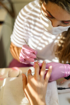 Manicurist inlays her client's nails with small elegant rhinestones 
