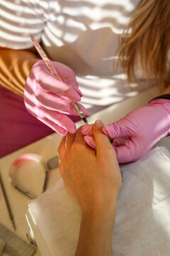 The manicurist covers her nails with a brush of clear gel nail polish