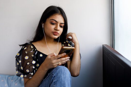 Young woman listening to music on mobile phone indoors