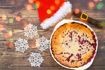 Christmas berry pie on a wooden background, Santa Claus hat.