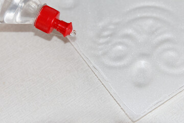 Process of applying universal glue from a bottle to the surface of a white molded foam board before being glued to the ceiling