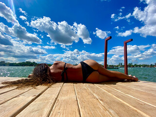 Summer, beautiful female sunbathing, next to the water, river,sea, in bikini or bathing suit