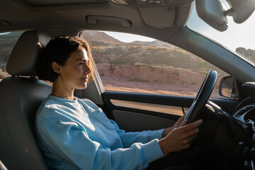 Woman with short hair looking at the window while sitting at the driver place