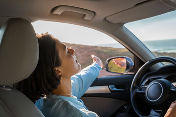 Woman with closed eyes sitting at the driver place at her car