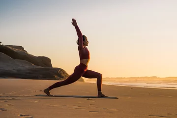 Poster Caucasian woman doing yoga exercises on the sand beach near the sea © Yakobchuk Olena