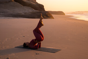 Calm woman practices headstand yoga on seaside beach