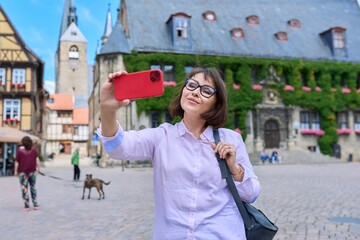 Woman tourist taking selfie in an old european city, in front of historical building