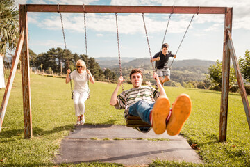 Family having fun on the swings at the park