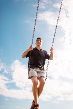 Smiling young man having fun on the swing