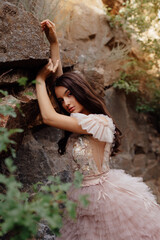 Fashionable young model in boho style dress on a background of rocks. Female beauty and style concept.