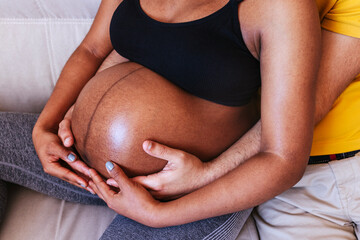 Crop pregnant woman in underwear sitting on bed