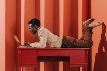 Fashionable portrait of a man in a geometric interior with a laptop