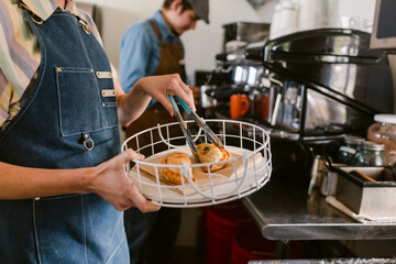 Crop barmaid with empanadas on tray at coffee shop