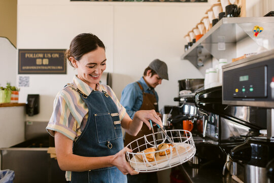 Happy waiter with empanadas on tray by espresso machine