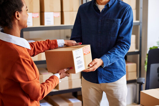 Woman giving parcel to man in delivery office