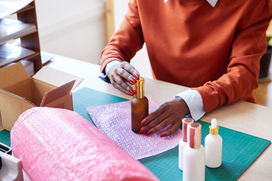 Cropped image of lady wrapping beauty product before shipment