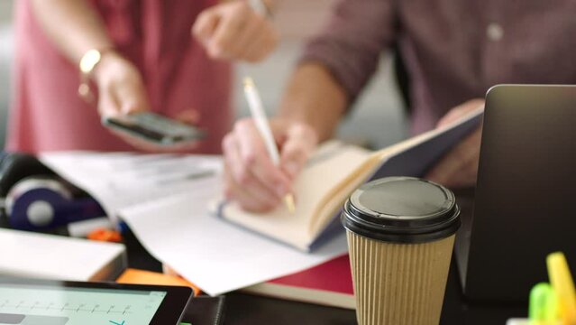 Creative business analysts using cellphone and paperwork to predict financial profit, loss or plan strategy in meeting. Startup design colleagues using technology to innovate progress from chart data