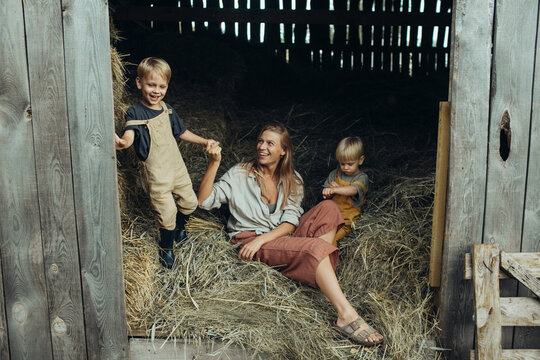 Mother and little sons play in the hayloft in the village