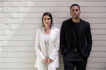 Confident male and female managers against brick wall