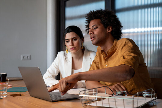 Multiracial colleagues analyzing data on laptop