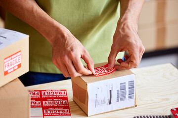 Crop post office worker marking parcel as fragile