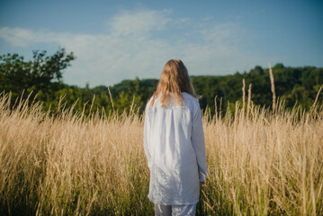 Beautiful girl dressed in Ukrainian national clothes stands in the middle of the field. Freedom concept