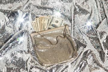 US dollar cash money in a glitz purse against glittering background