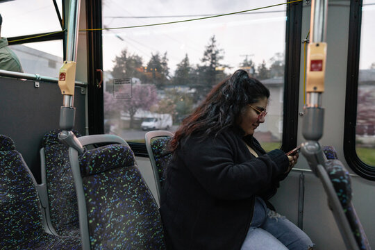 Young person using cell phone on the bus.