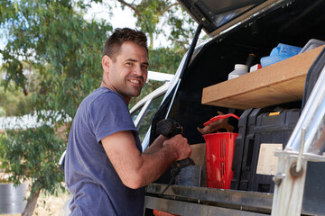 Smiling tradesman standing next to his work truck