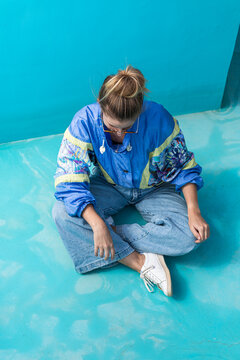 A Young Woman Wearing A Retro 90s Jacket Inside Of A Empty Blue Pool