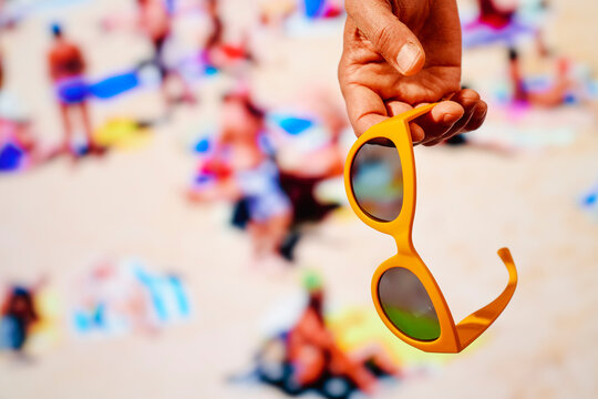 is holding a pair of yellow sunglasses in his hand