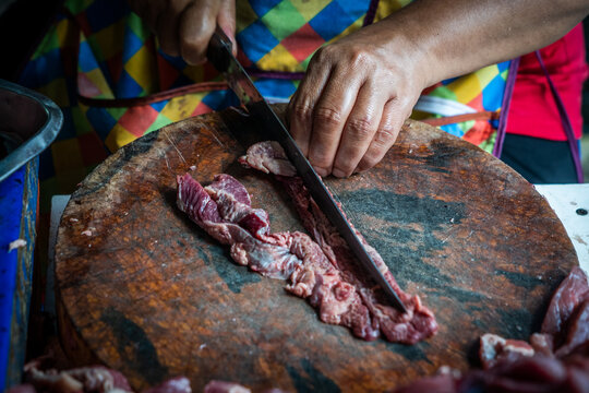 A street butcher chops pork