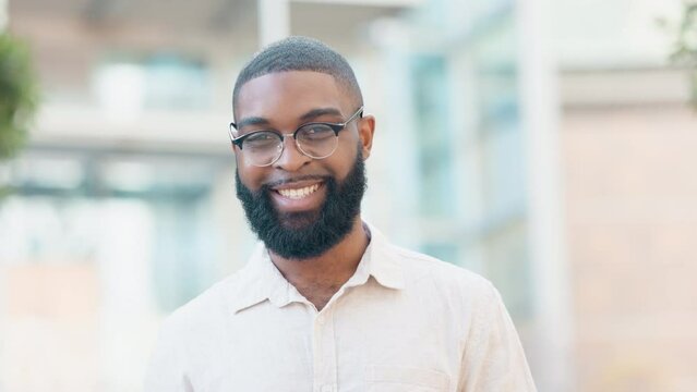 A stylish male student wearing glasses outdoors in the city. A confident trendy entrepreneur with a beard standing outside in an urban town. Portrait of smart and confident black man with spectacles