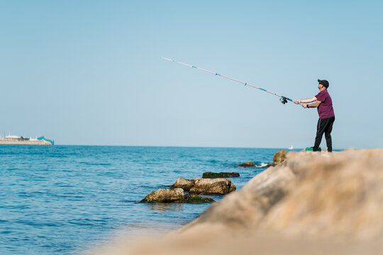 Fisherman pulling rod during fishing at seafront
